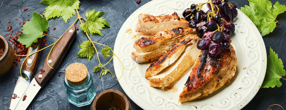 Roast chicken breast with grapes.Summer BBQ.Barbecued chicken meat.. Grilled chicken fillets