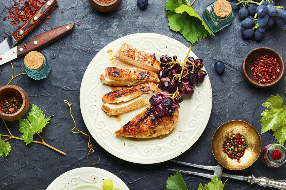 Roast chicken breast with grapes.Summer BBQ.Barbecued chicken meat.. Sliced chicken breast with spices