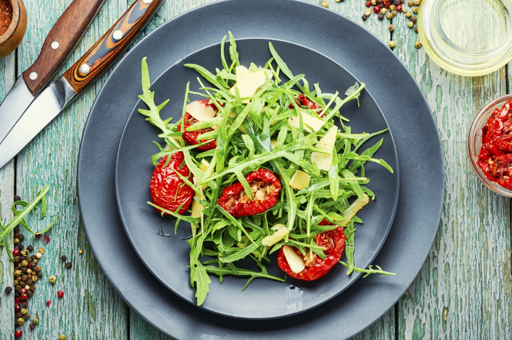Appetizing salad with arugula, sun-dried tomatoes and cheese.Healthy green salad. Salad with sun dried tomatoes and arugula