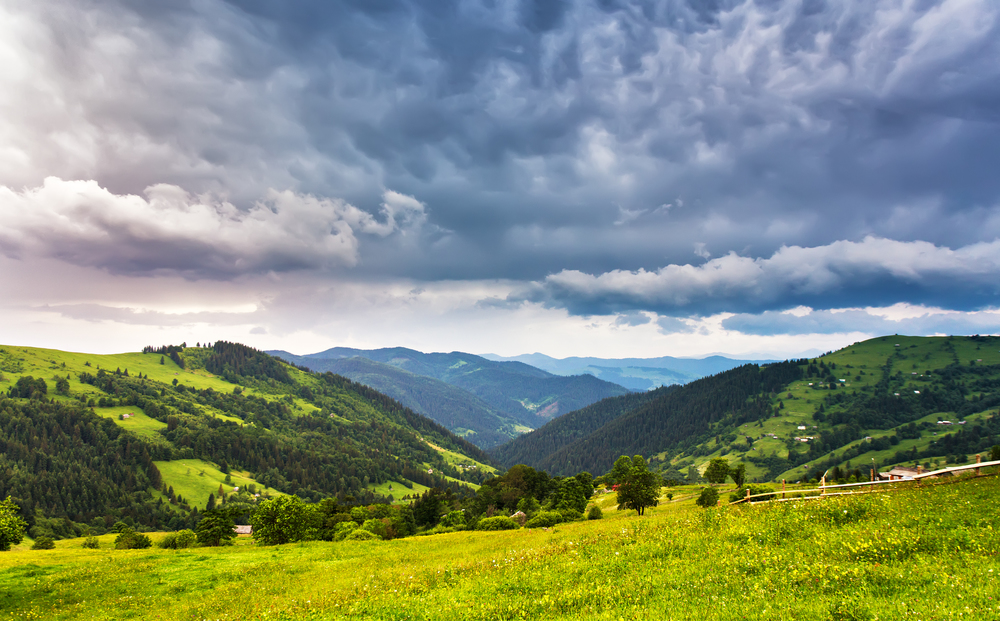 Summer mountain stormy rural landscape. Rain in mountain valley. Dramatic sky on background. Europe travel, Carpathians, Ukraine.