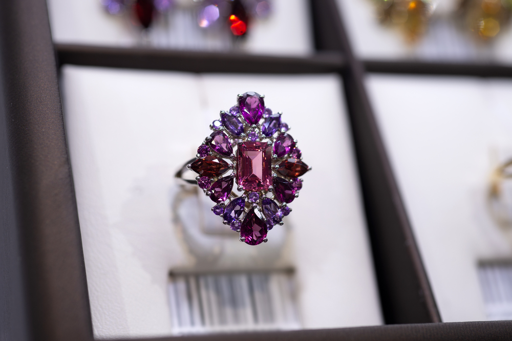 jewelry retail store showcase displaying white gold ring  with precious  gemstones. ring with amethysts, turmakins. close up