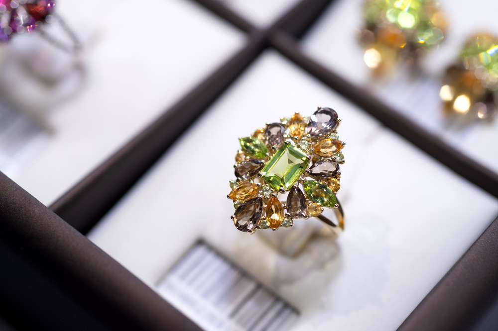 jewelry retail store showcase displaying white gold ring  with precious  gemstones. ring with emeralds, citrines, topazes. close up