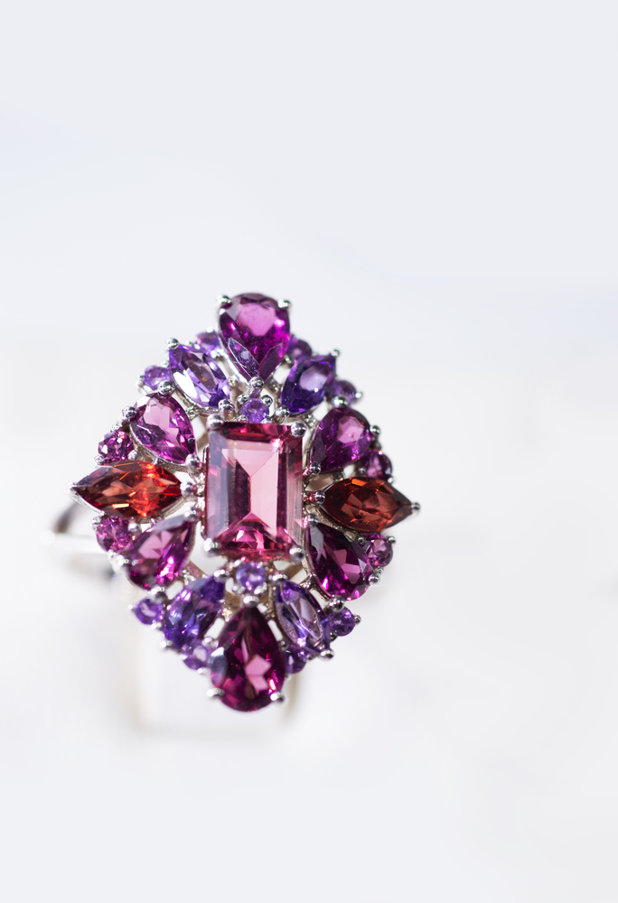 jewelry retail store showcase displaying white gold ring  with precious  gemstones. ring with amethysts, rubies, turmalines. close up