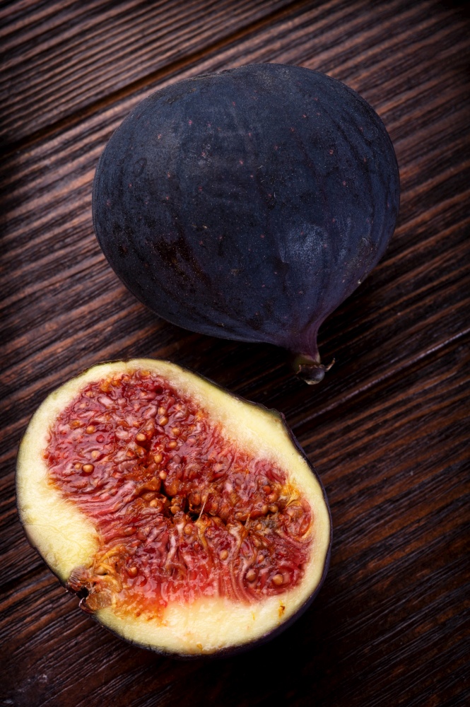 tasty ripe purple  fig with cutting  half  on wooden table. close up