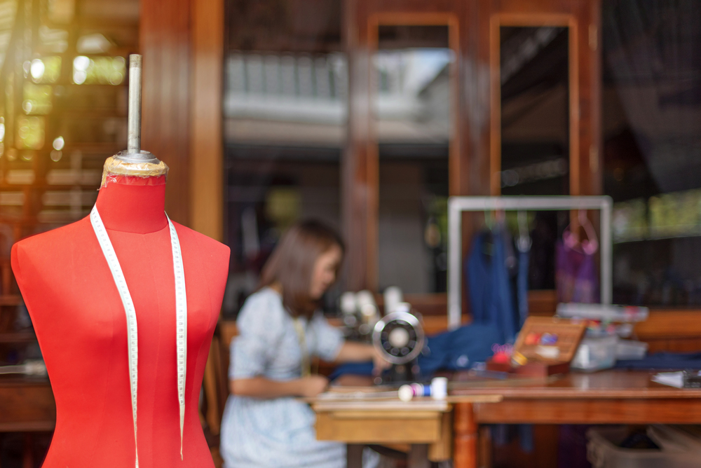 Red dummy with measuring tape in tailors studio. sewing workshop,. Beautiful asian dressmaker in workroom