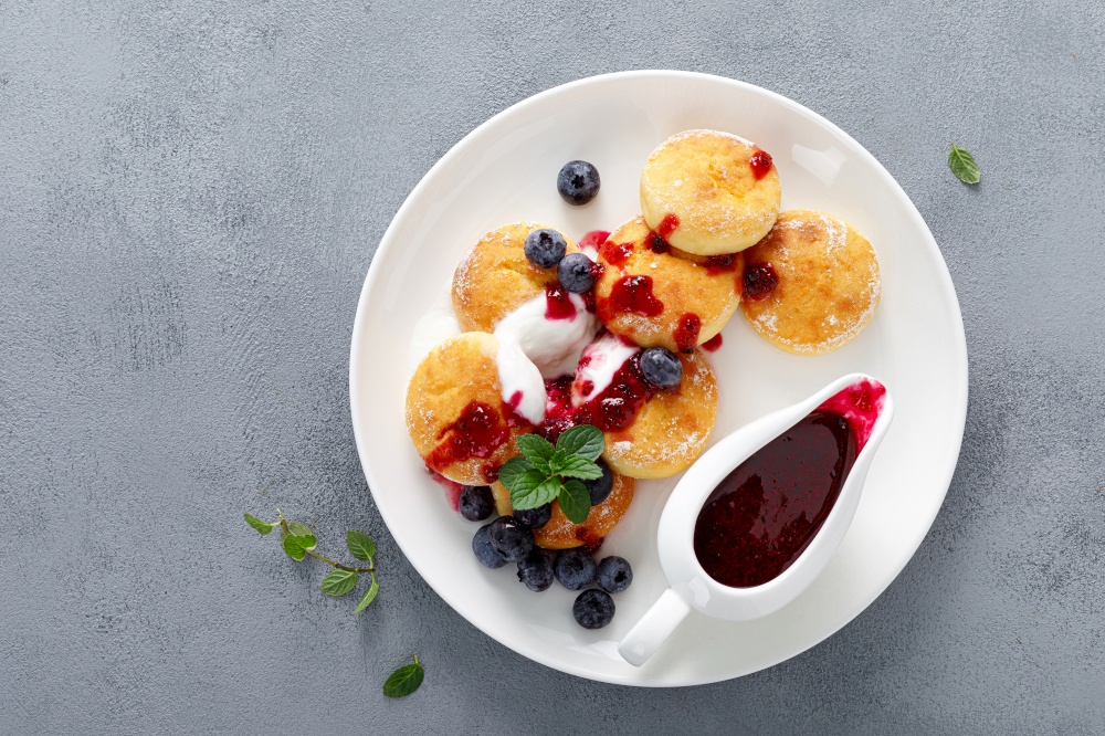 Baked cottage cheese pancakes, syrniki with yogurt, blueberry sauce and fresh berries