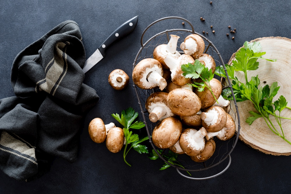Raw mushrooms champignons on black background, cooking fresh champignons