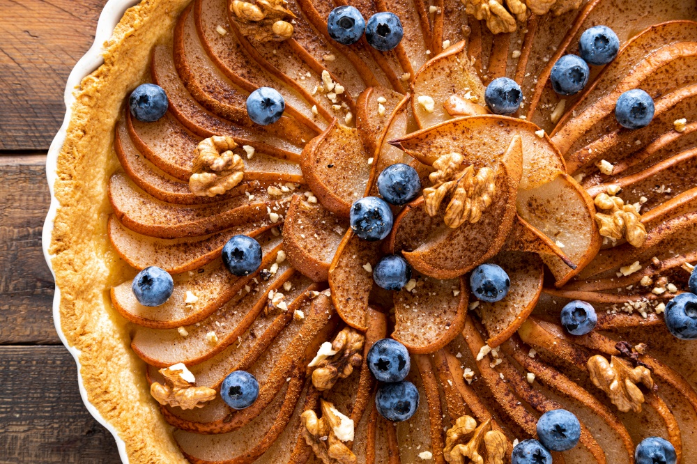 Thanksgiving pear tart, pie or cake with fresh pears and blueberry, cinnamon and walnuts