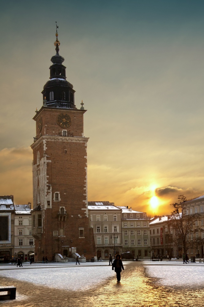 Winter sunlight and the Town Hall Tower at dusk in the main square (Rynek Glowny) in the old town district of Krakow in Poland.