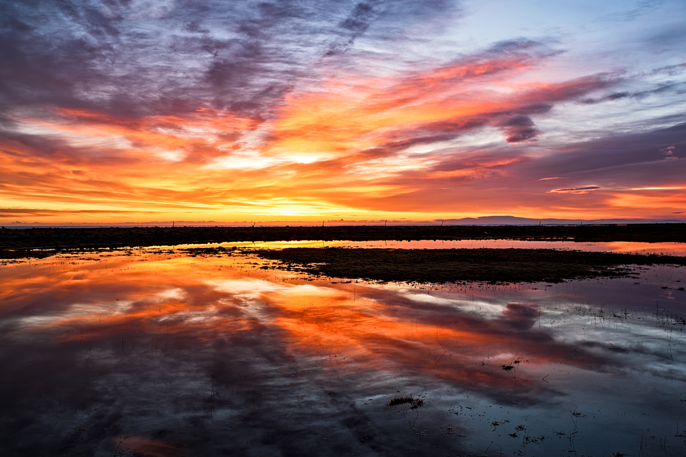 Majestic sunset with clouds reflected in the water. Colorful sunset reflected in the water