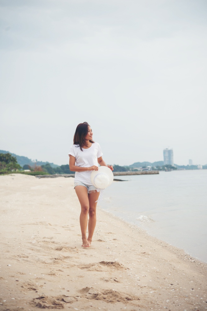 Portrait of young woman walking on the beach barefoot.