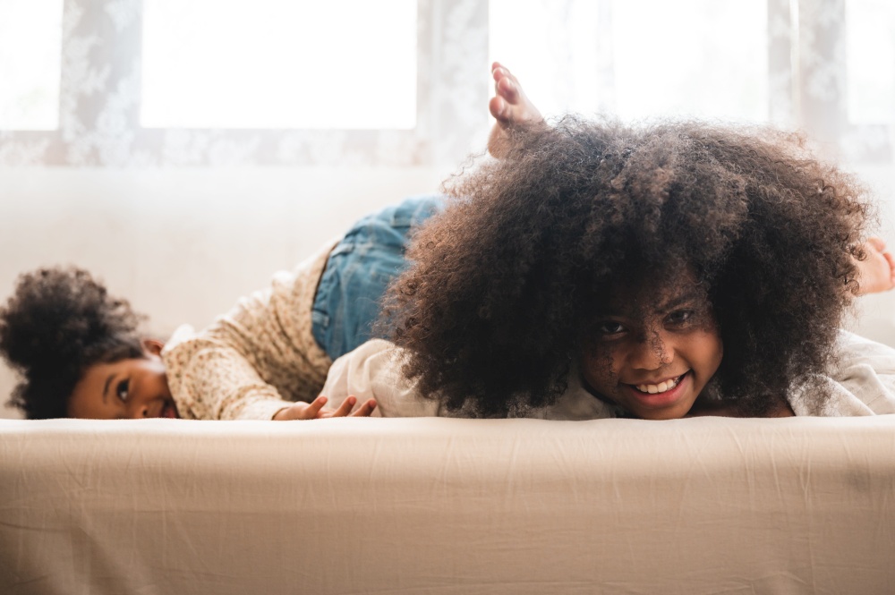 African American children relax playing on the bed at home