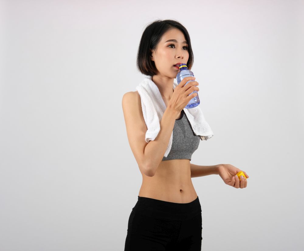 sporty fitness woman in sportswear drinking water on white background. healthy sport lifestyle