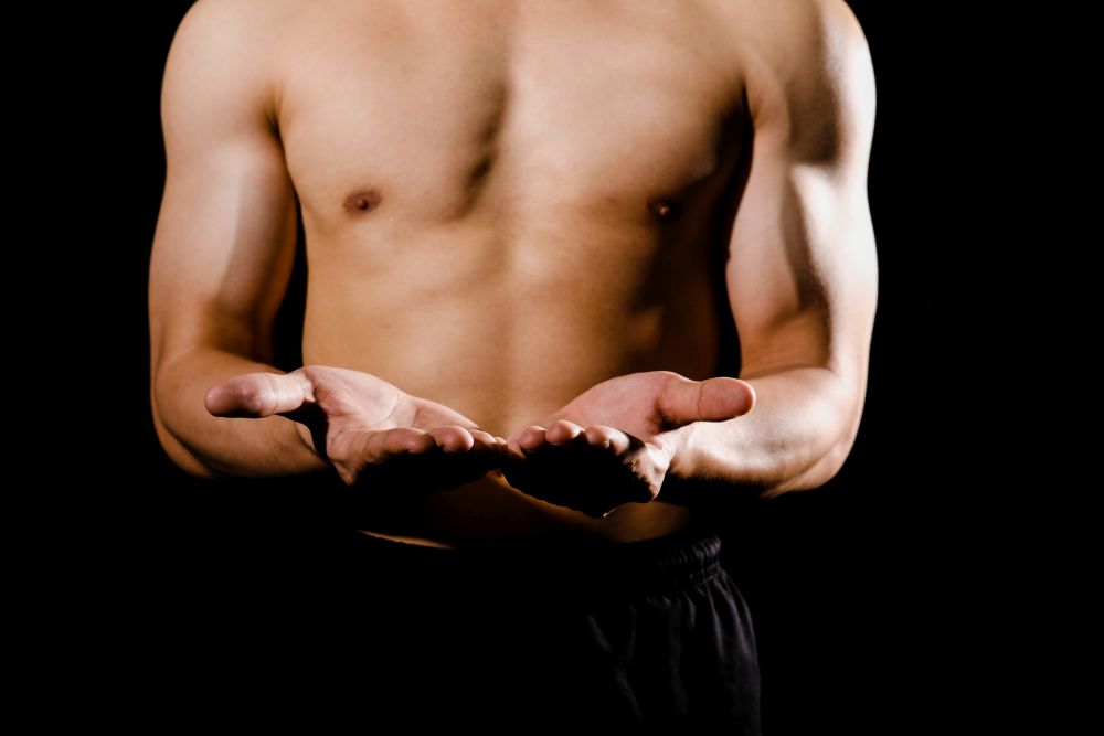 portrait of athletic muscular bodybuilder man with naked torso six pack abs showing copy space. fitness workout concept