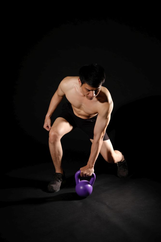 portrait of athletic muscular bodybuilder man with naked torso six pack abs working out with kettle bell. fitness sport exercise concept