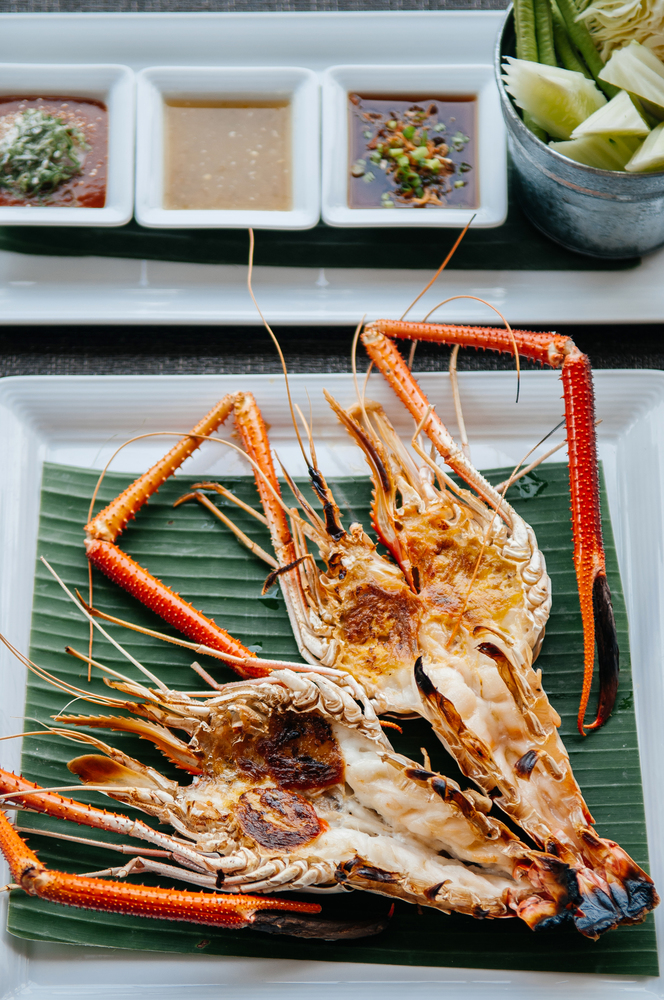 Thai Ayutthaya cuisine grilled giant river prawns serving on banana leaf with assorted seafood sauce
