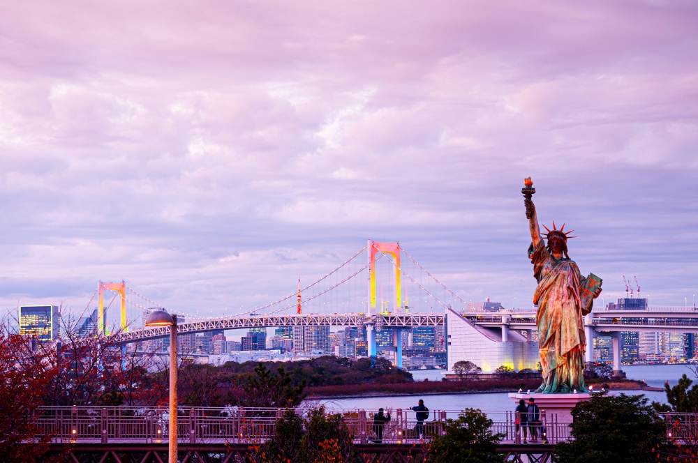 DEC 5, 2019 Tokyo, Japan - Odaiba Rainbow bridge and statue of Liberty with illuminated colourful light and Tokyo bay view at evening pinkish sky