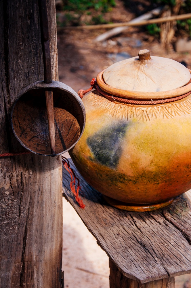 Thai style ceramic water pot with lid and water dipper made from coconut shell. Thai culture water pot for welcome drink