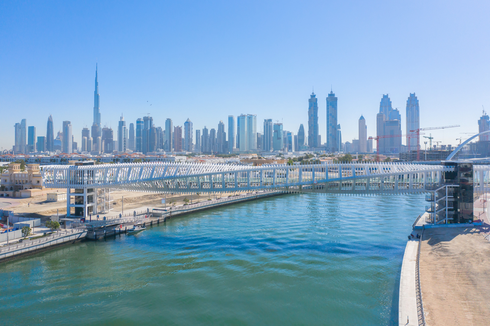 Aerial view of twisted Bridge. Structure of architecture with lake or river, Dubai Downtown skyline, United Arab Emirates or UAE. Financial district and business area in urban city with blue sky.