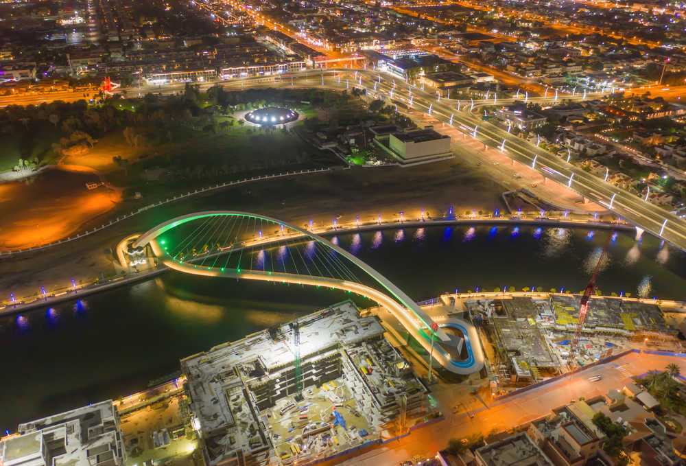 Aerial view of Tolerance bridge and Dubai downtown skyline. Structure of architecture with lake or river, United Arab Emirates or UAE. Financial district and business area in urban city at night.