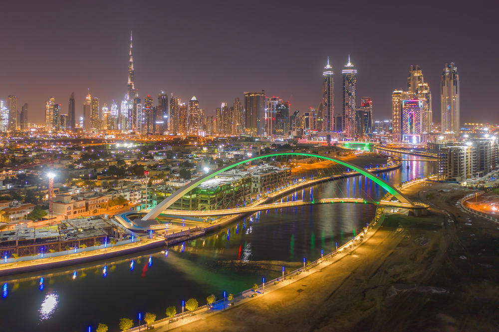 Aerial view of Tolerance bridge and Dubai downtown skyline. Structure of architecture with lake or river, United Arab Emirates or UAE. Financial district and business area in urban city at night.