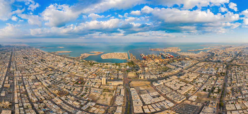 Aerial view of container cargo ship in the export and import business and logistics international goods in urban city. Shipping to the harbor by crane in Dubai Harbour, UAE