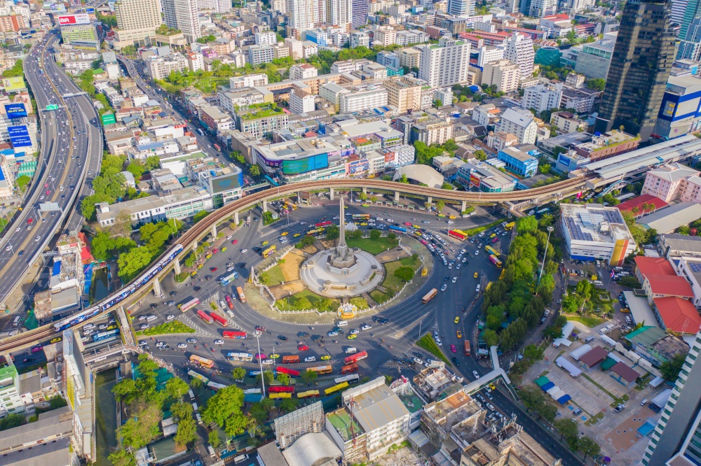 Aerial view of Victory Monument on busy street road. Roundabout in Bangkok Downtown Skyline. Thailand. Financial district center in smart urban city. Skyscrapers at sunset.