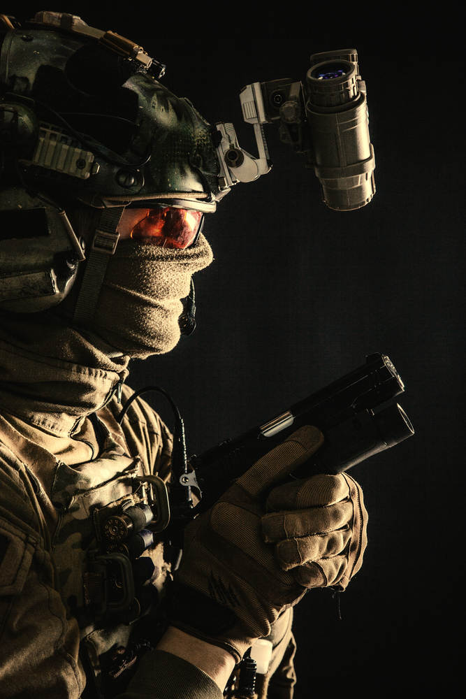 Army elite commando, professional mercenary, counter-terrorist tactical team fighter in combat helmet, equipped night-vision device, creeping in darkness with service pistol in hand, studio shoot. Elite commando soldier sneaking with pistol in hand