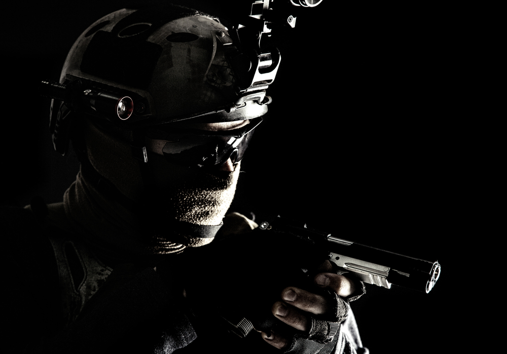 Army counter-terrorism squad, police SWAT team fighter hiding identity behind mask and glasses, wearing helmet with night vision-device, creeping in darkness, aiming service pistol during mission. Police SWAT team fighter aiming service pistol