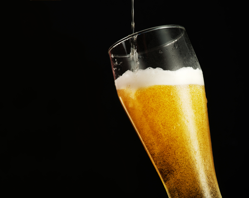 Pouring beer into glass over black background