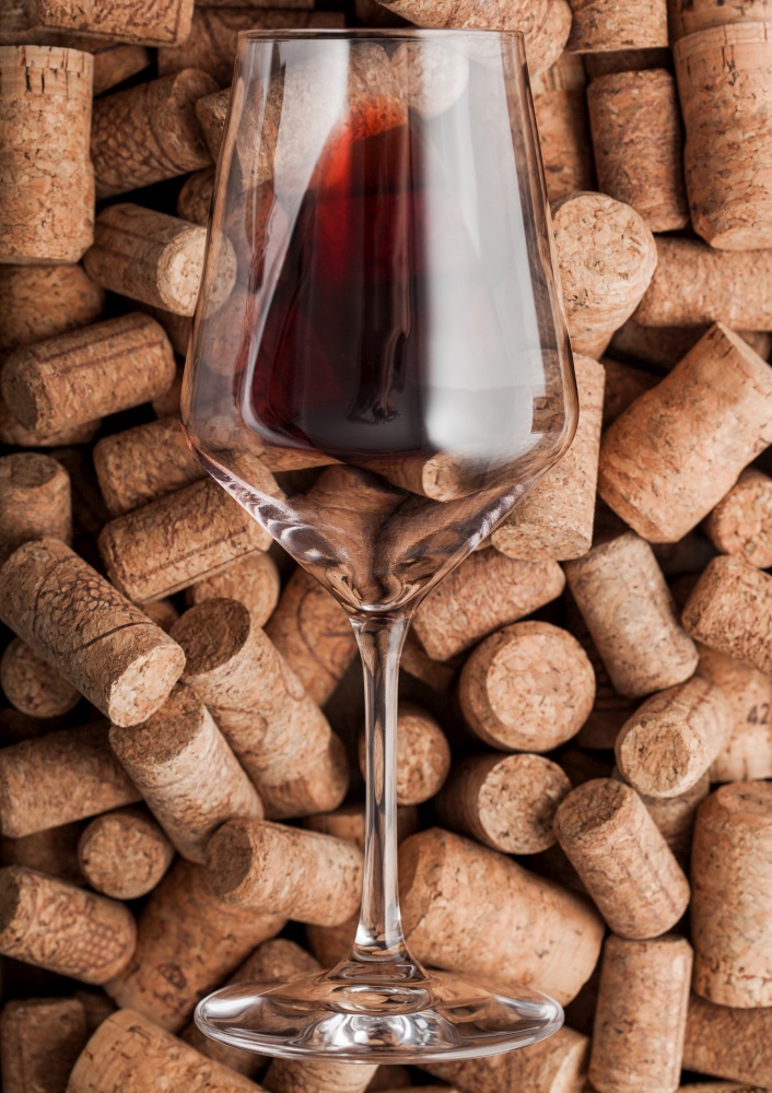 Luxury glass of red wine on top of various wine corks. Macro
