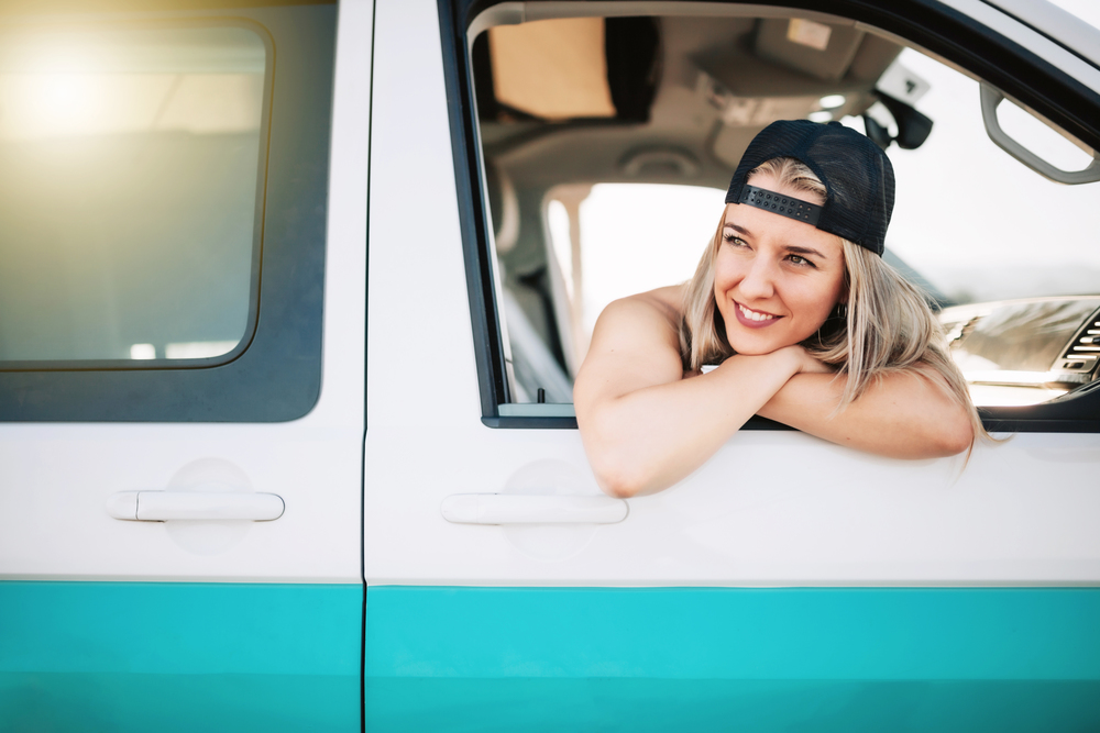 Young smiling woman looks out the window of the van