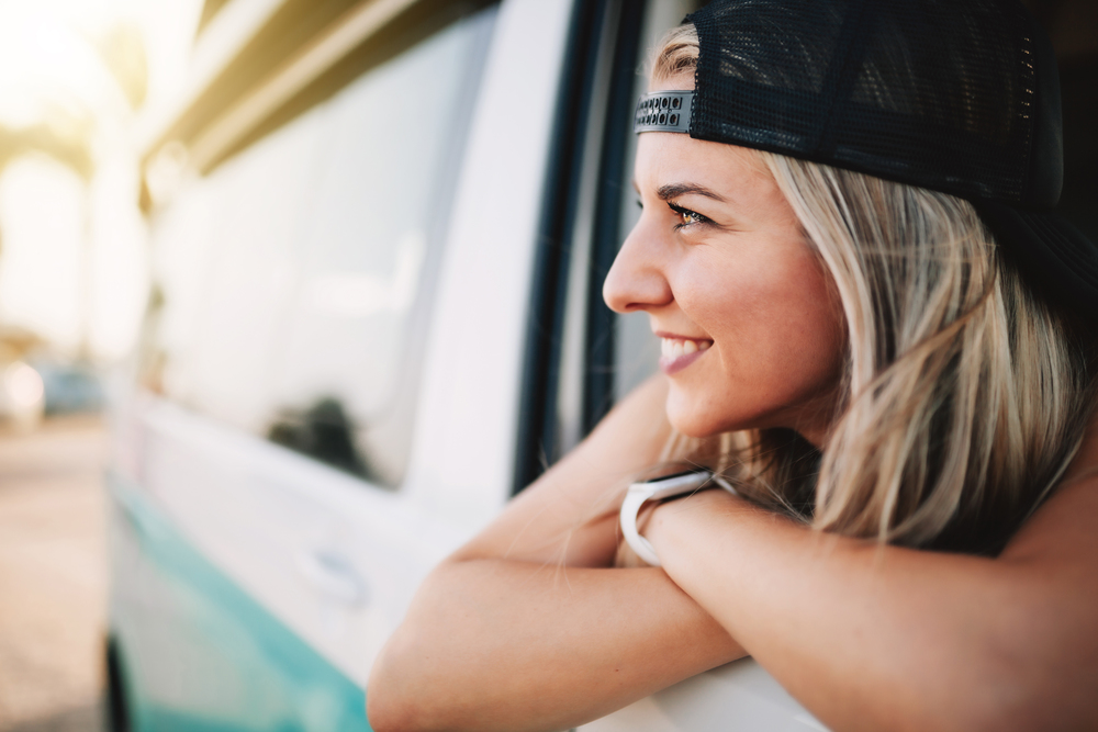 Young smiling woman looks out the window of the van