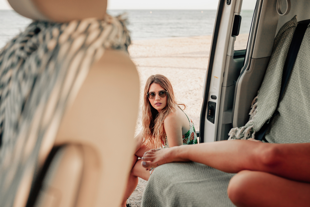 Two young women inside de van near the beach with bare legs