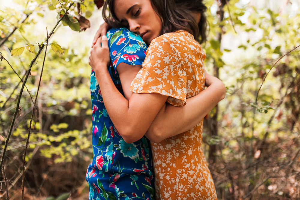 Two hugged women surrounded by forest plants