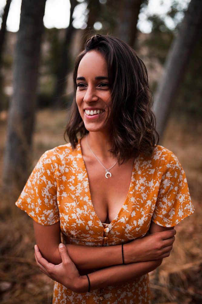 Young smiling woman embraced herself wearing dress in the forest