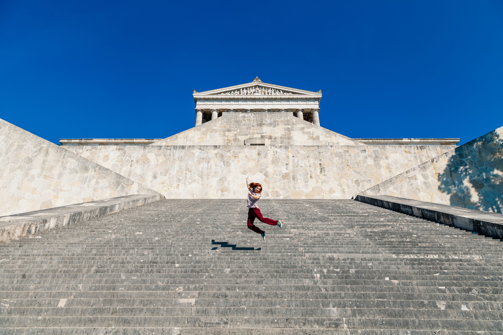 Young woman jumping on the walhalla stone stairs in germany
