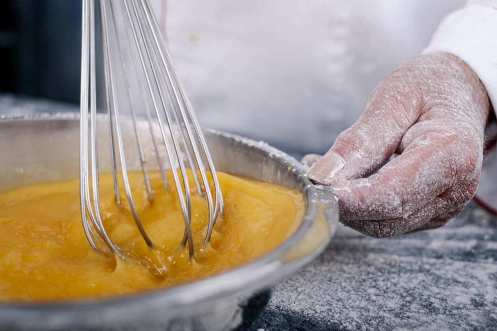 close-up of a baker&rsquo;s hand moving a hand blender in a muffin bowl