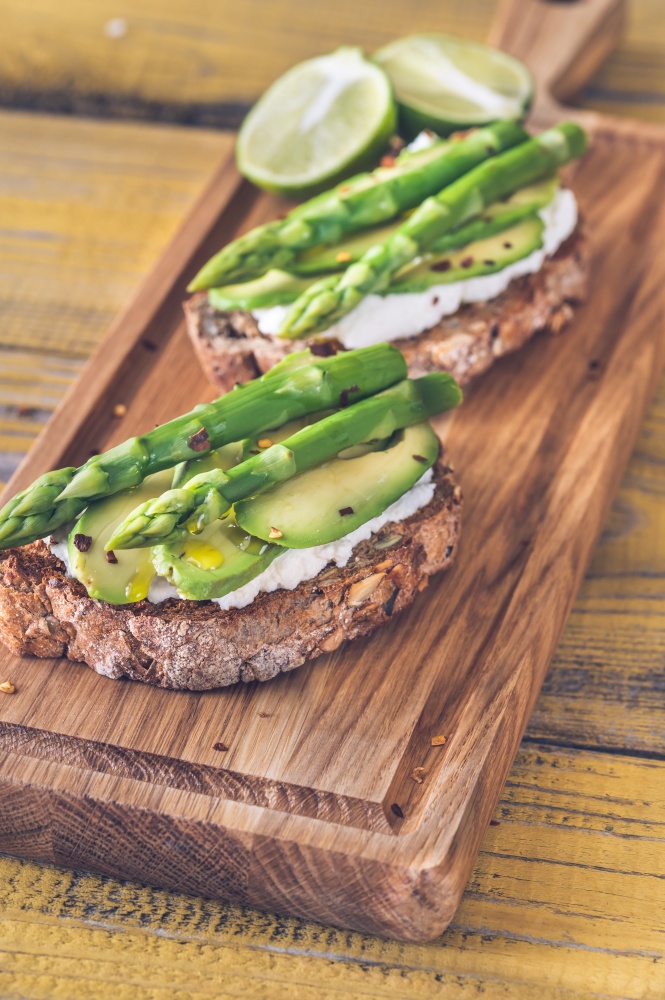 Avocado asparagus toasts with ricotta on cutting board