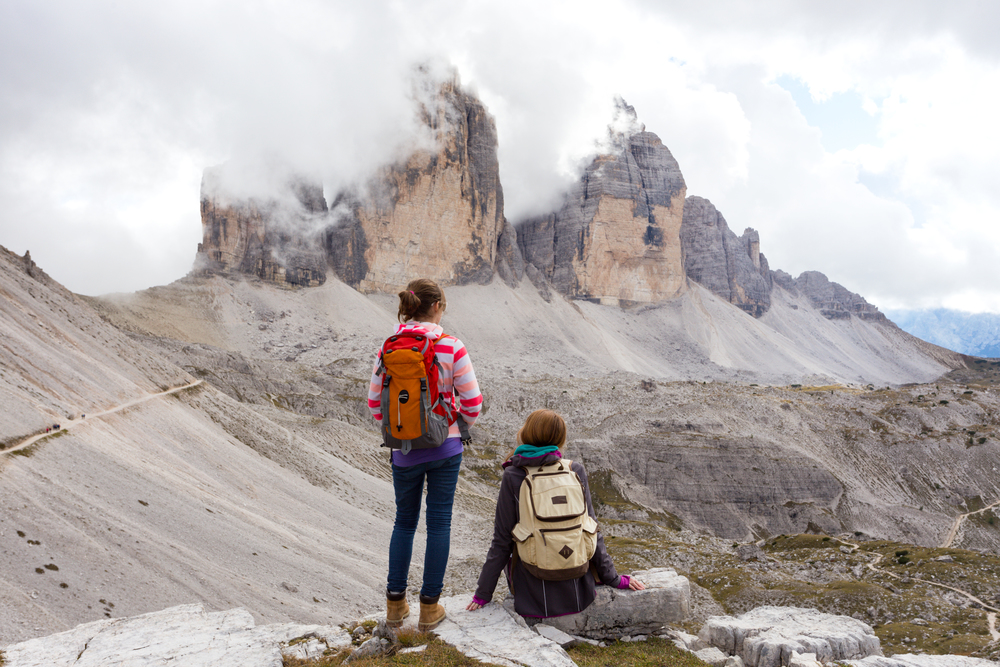 two girls hikers resting and looking at the rocks. tre cime di lavaredo