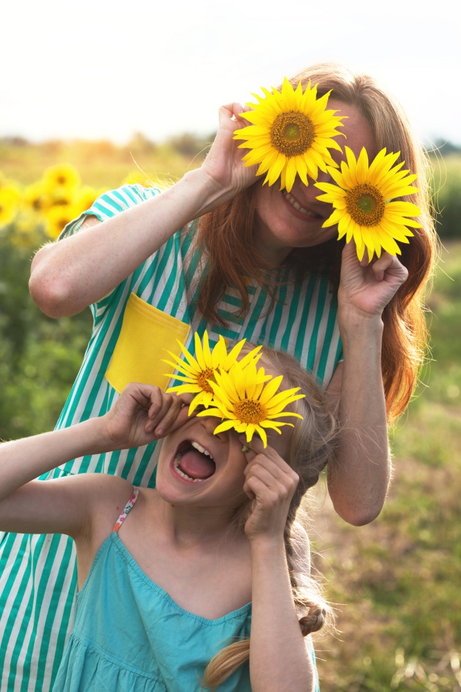 Crazy happy girls in a field of sunflowers at sunset. family - mom and daughter. Ukraine.