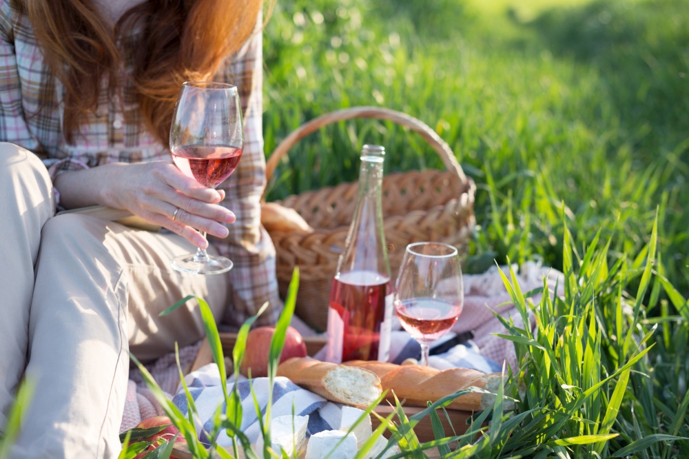 Summer - Provencal picnic in the meadow.  girl with a glass of wine  near a picnic basket and baguette