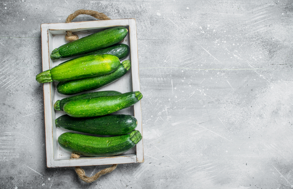 Green zucchini on tray. On white rustic background. Green zucchini on tray.