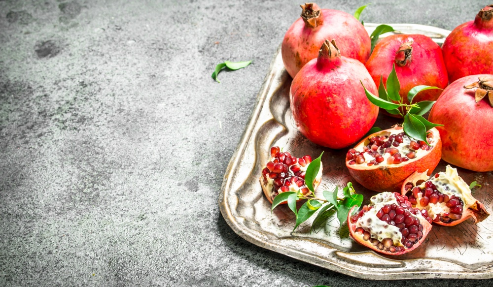 Ripe pomegranates on a steel tray. On a rustic background.. Ripe pomegranates on a steel tray.
