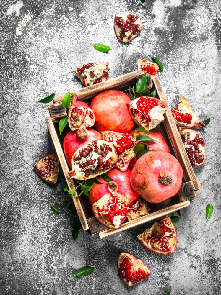 Ripe pomegranates in a box. On a rustic background.. Ripe pomegranates in a box.