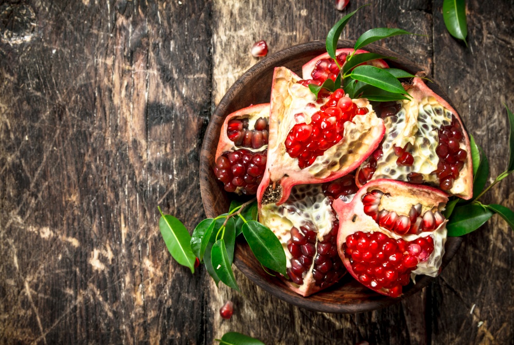Pieces of fresh pomegranate in a bowl. On a wooden background.. Pieces of fresh pomegranate in a bowl.