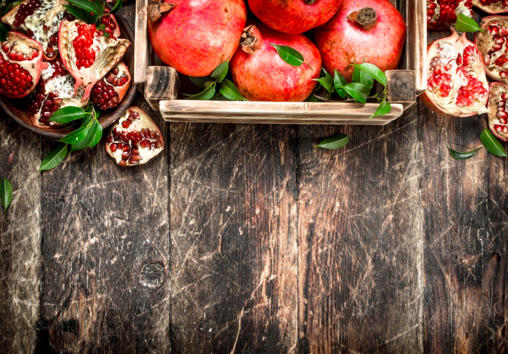 Fresh pomegranates in an old box. On a wooden background.. Fresh pomegranates in an old box.