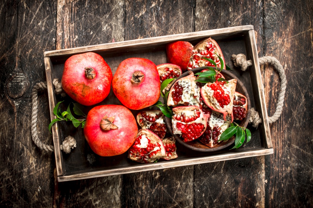 Fresh pomegranates on a tray. On a wooden background.. Fresh pomegranates on a tray.