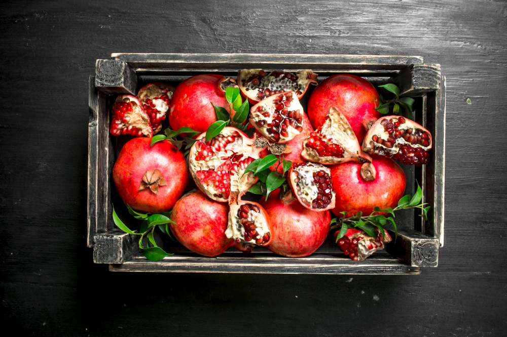 Fresh pomegranates in a box. On the black chalkboard.. Fresh pomegranates in a box.