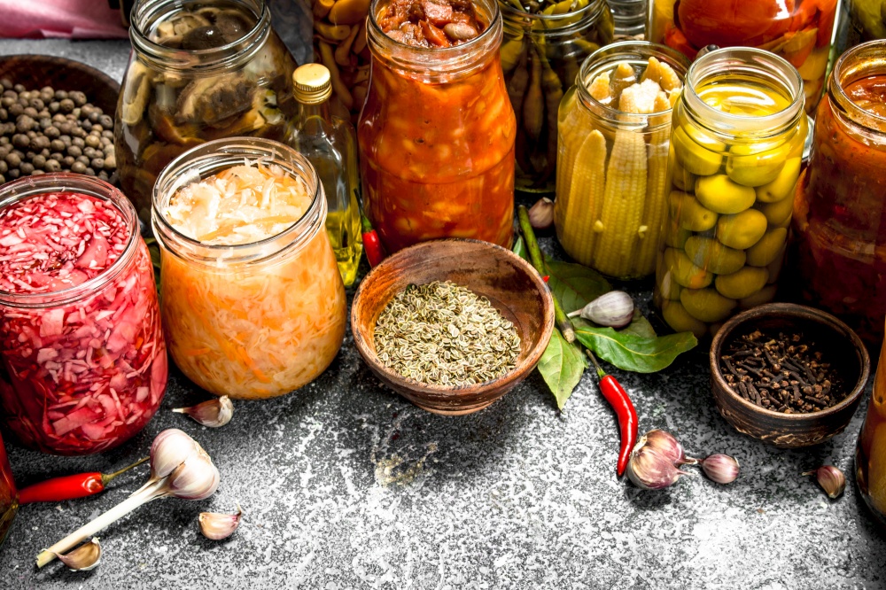 Marinated vegetables with spices in glass jars. On a rustic background.. Marinated vegetables with spices in glass jars.